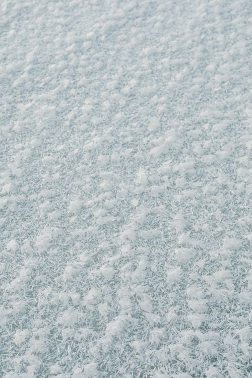 Free Close-up view of frosty snow texture, capturing the intricate natural patterns in winter. Stock Photo