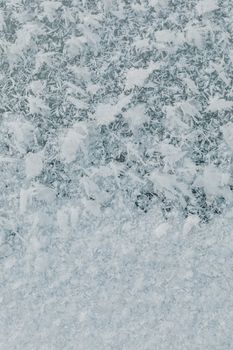 Detailed view of ice crystal patterns on a frosty winter window surface.