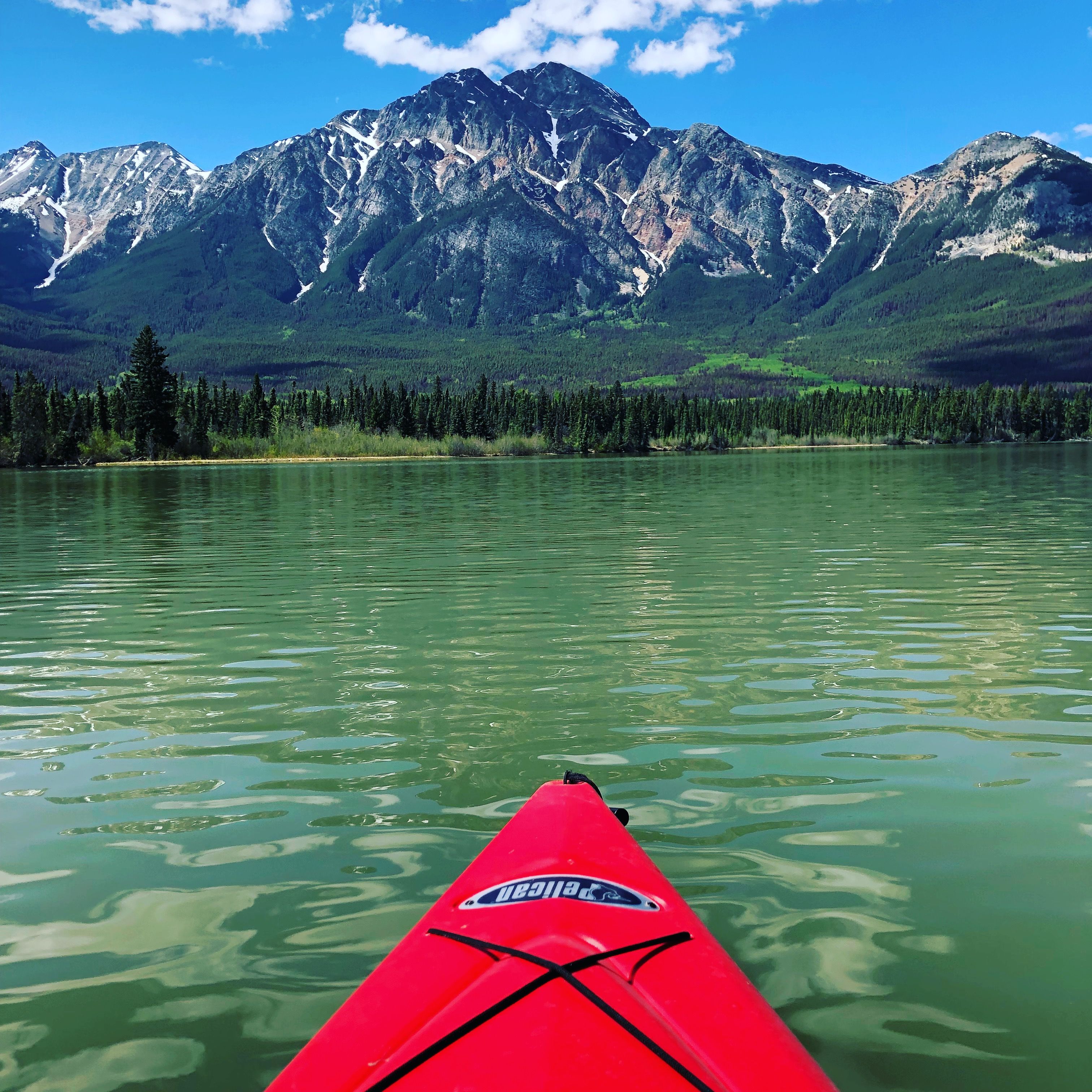 Scenic view of kayaking in Jasper National Park with majestic mountains and clear lake.