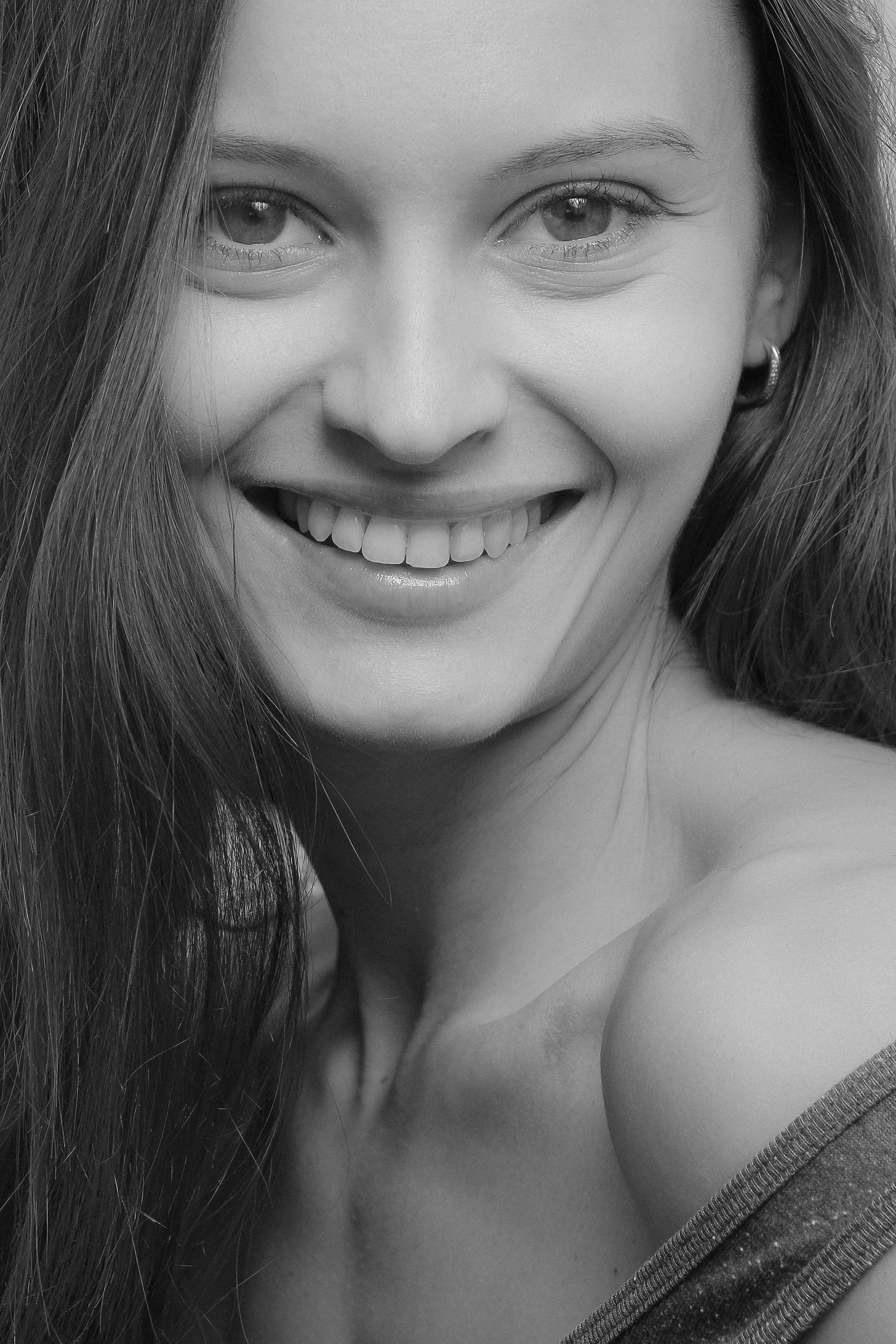 Close-up black and white portrait of a smiling woman, showcasing elegance and natural beauty.