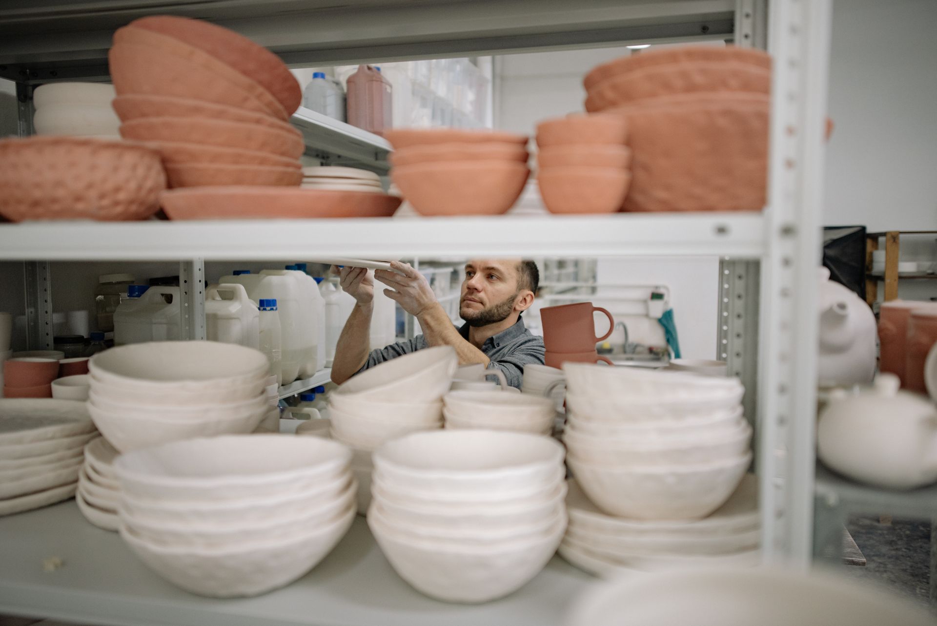 A Bearded Man Stacking Bowls on Shelves