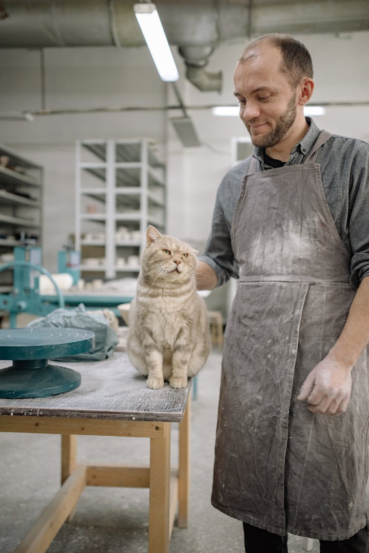 
A Man In An Apron Petting His Cat