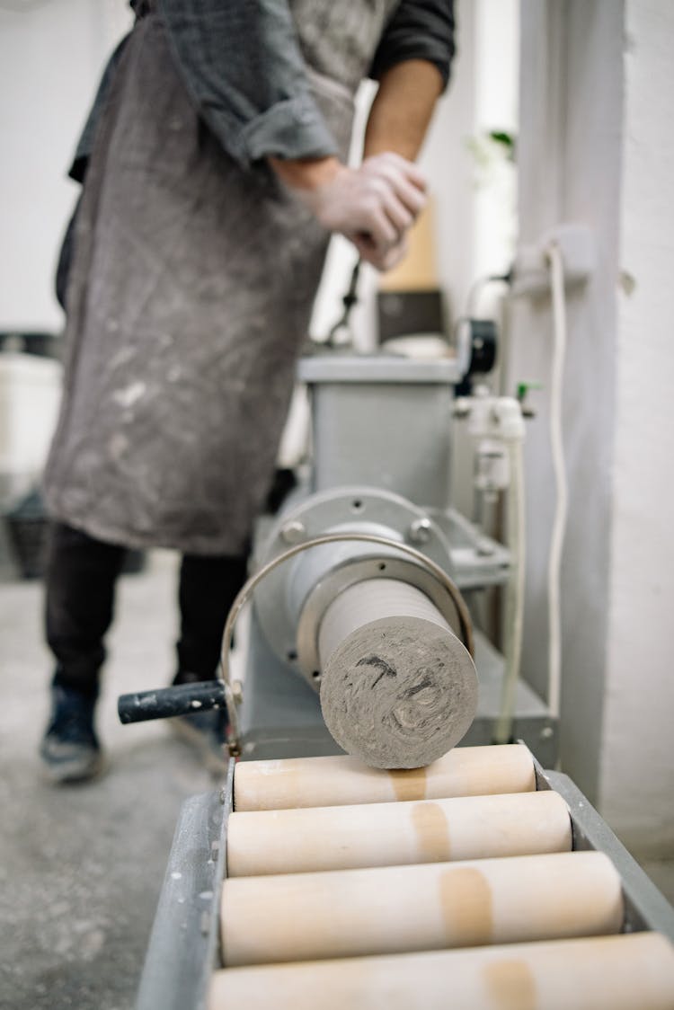 Man Shaping Block Of Clay Into Cylinder