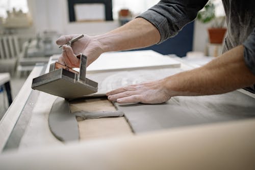Man Working with Clay on Table in Workshop