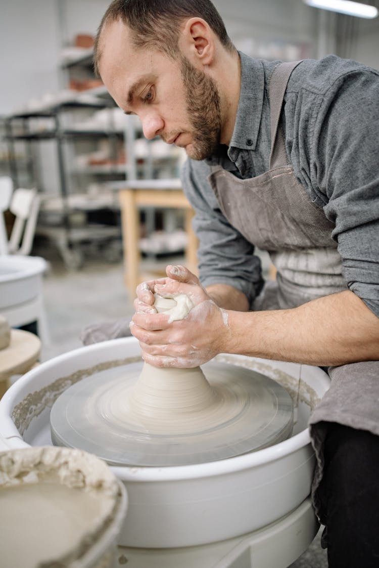 A Bearded Man Sculpting A Clay Pot On A Pottery Wheel