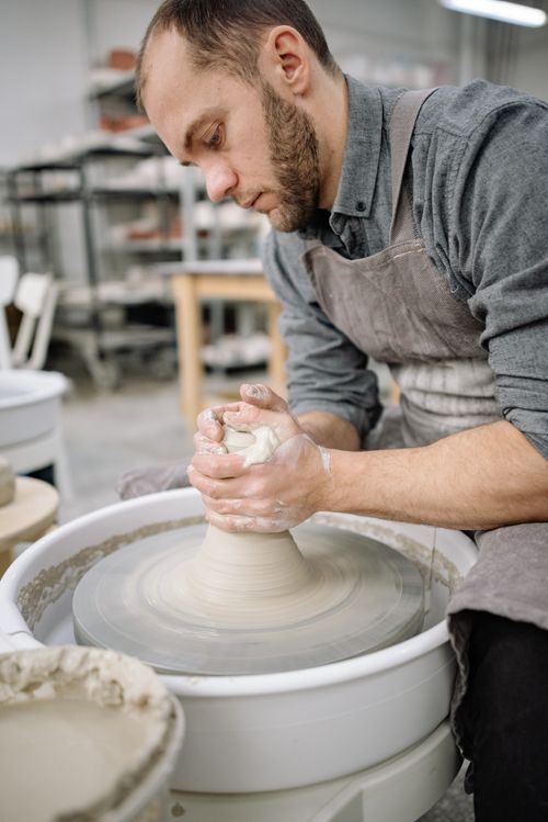 Free A skilled potter shaping clay on a pottery wheel, showcasing craftsmanship and creativity. Stock Photo