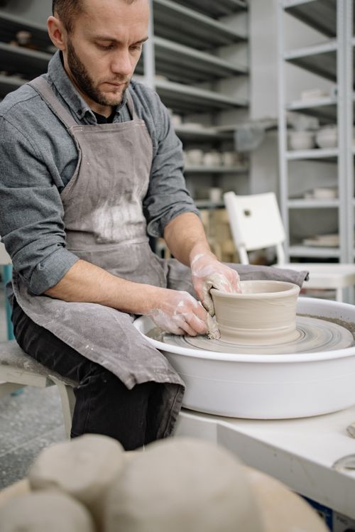 Free An artisan potter focused on crafting a clay pot with precision on a pottery wheel. Stock Photo