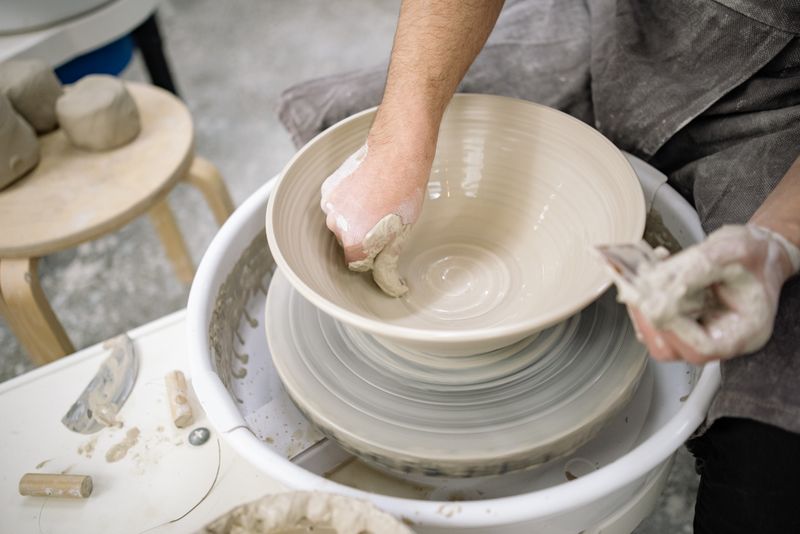 Potter trimming the foot of a thrown bowl with a steel tool