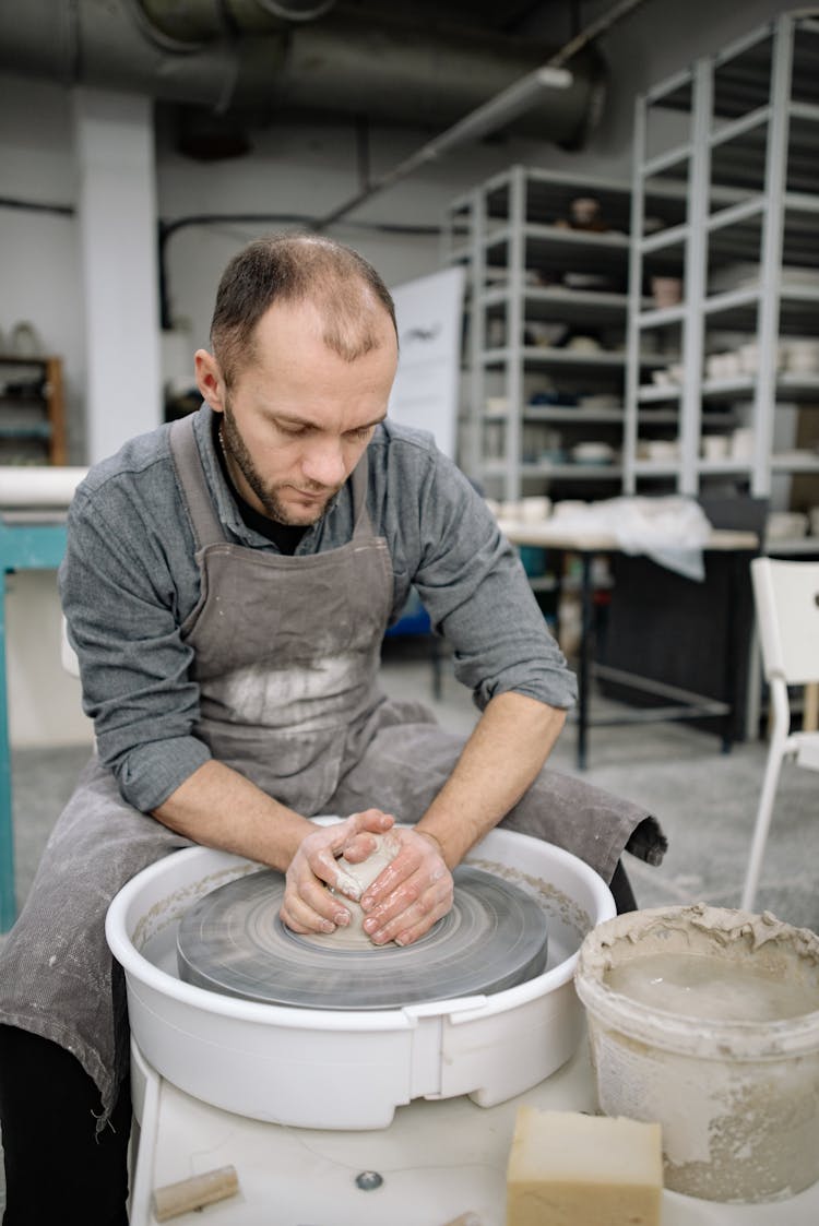 Potter Forming Clay On The Pottery Wheel 