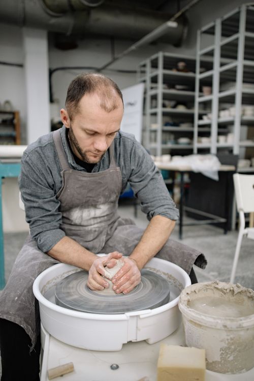 Free A skilled potter concentrates while working on a pottery wheel in a workshop, crafting a clay masterpiece. Stock Photo