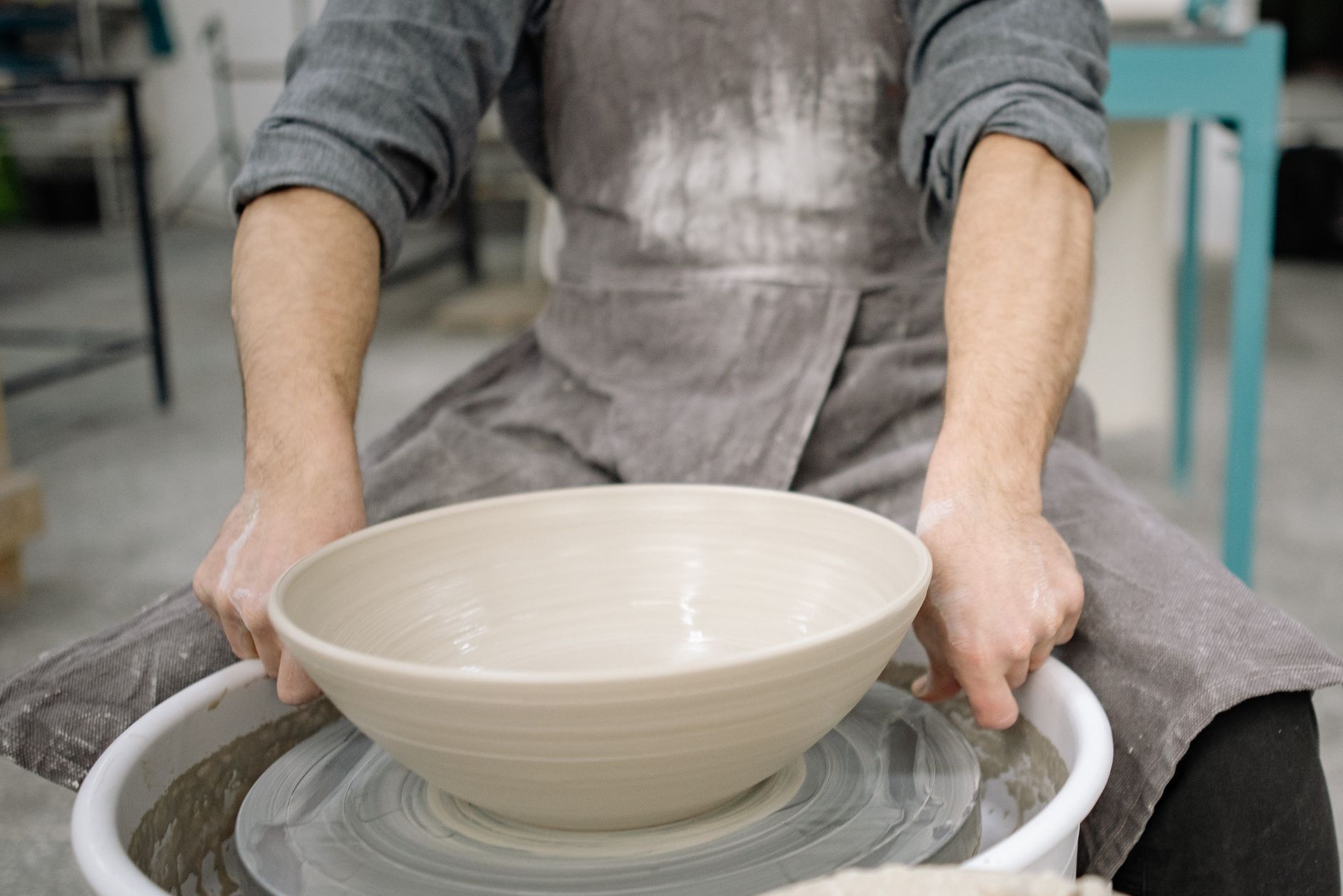Close-up of hands shaping a ceramic bowl on a potter's wheel in a workshop.