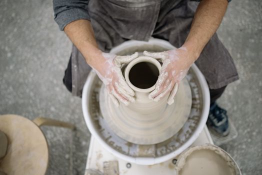 Hands shaping pottery on a wheel in an artisan workshop. A creative process in action.
