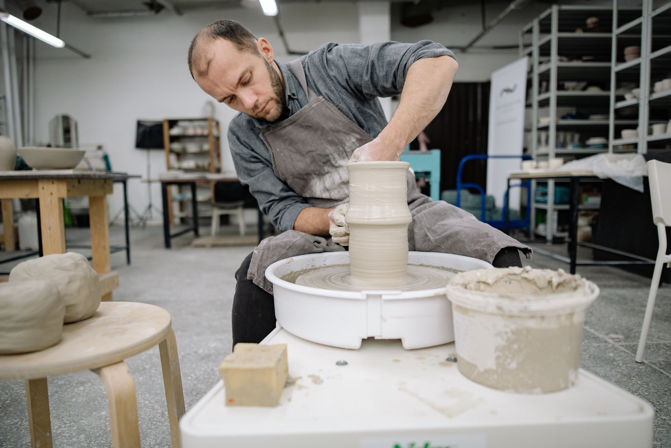 Hands shaping clay on a pottery wheel