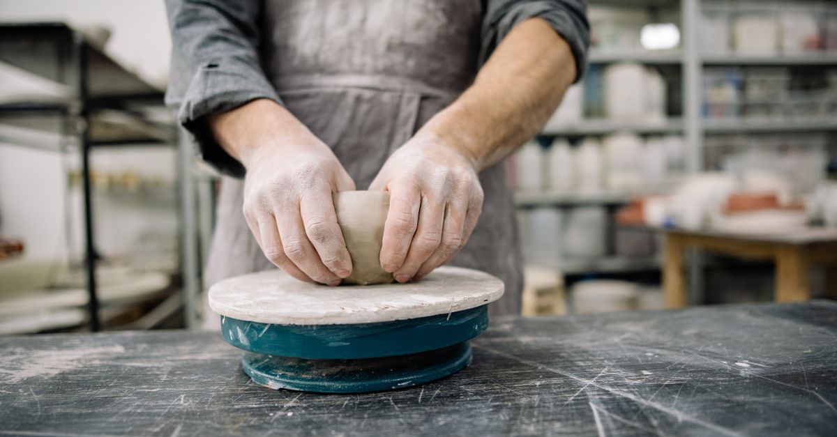 A potter expertly shaping clay on a wheel in a pottery studio, showcasing craftsmanship.