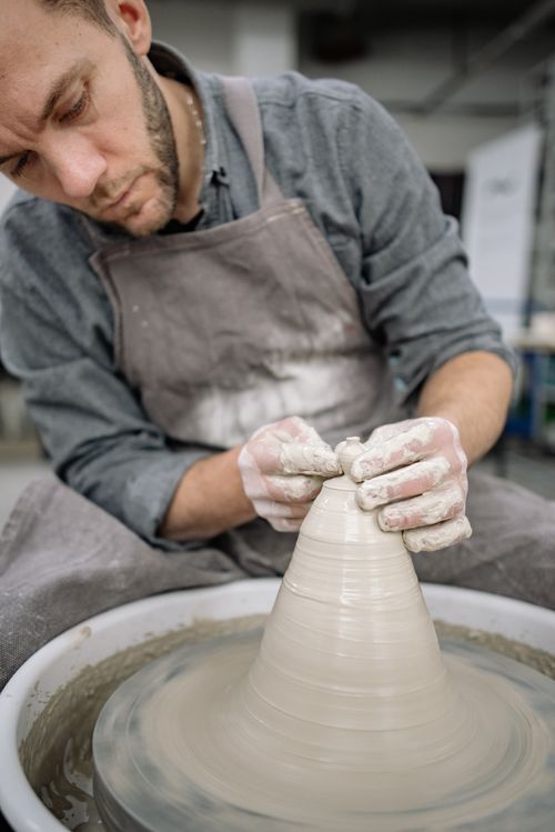Free A skilled artisan attentively shapes wet clay on a pottery wheel. Stock Photo