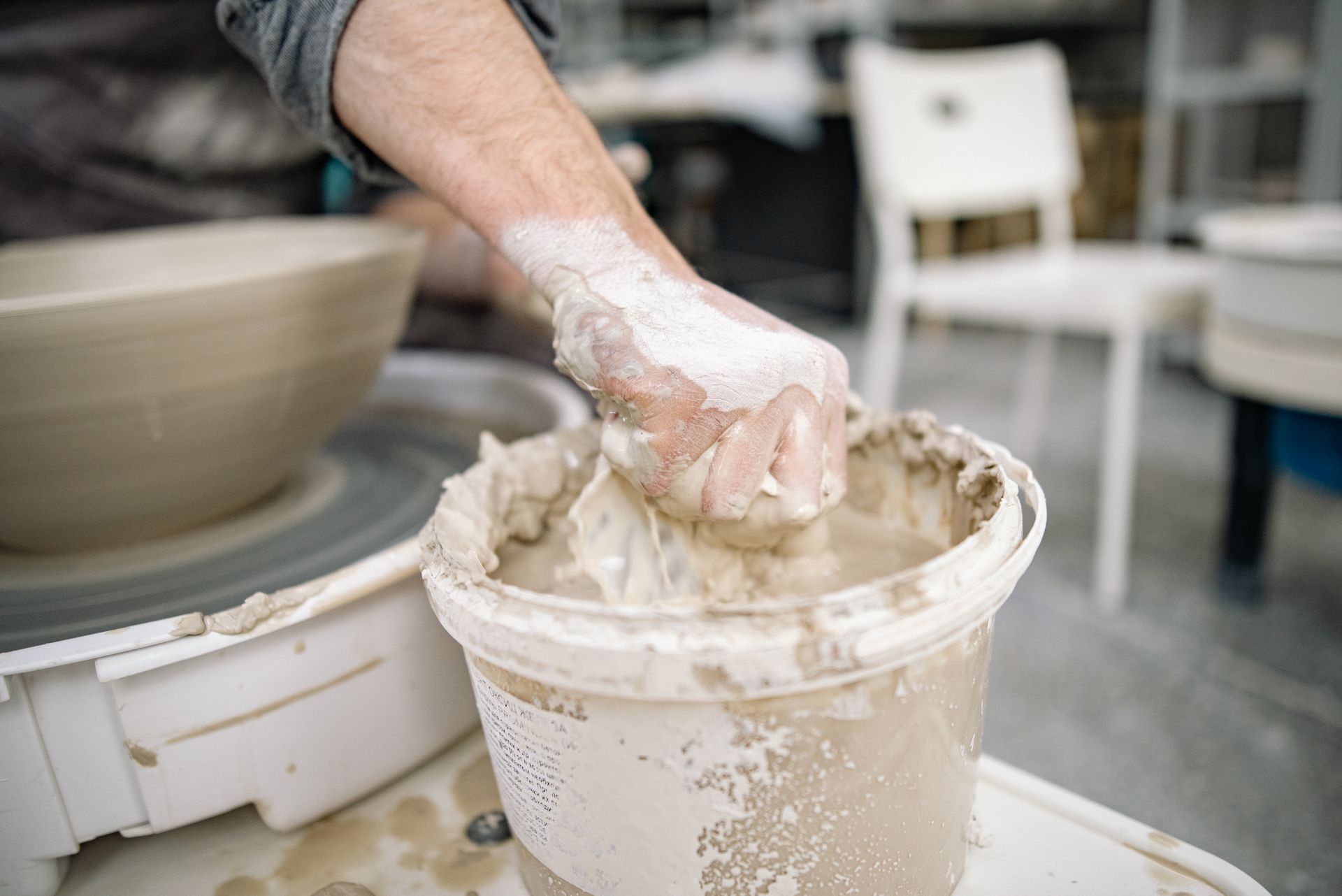 A close-up of an artisan's hand molding clay on a pottery wheel, capturing the art of craftsmanship.