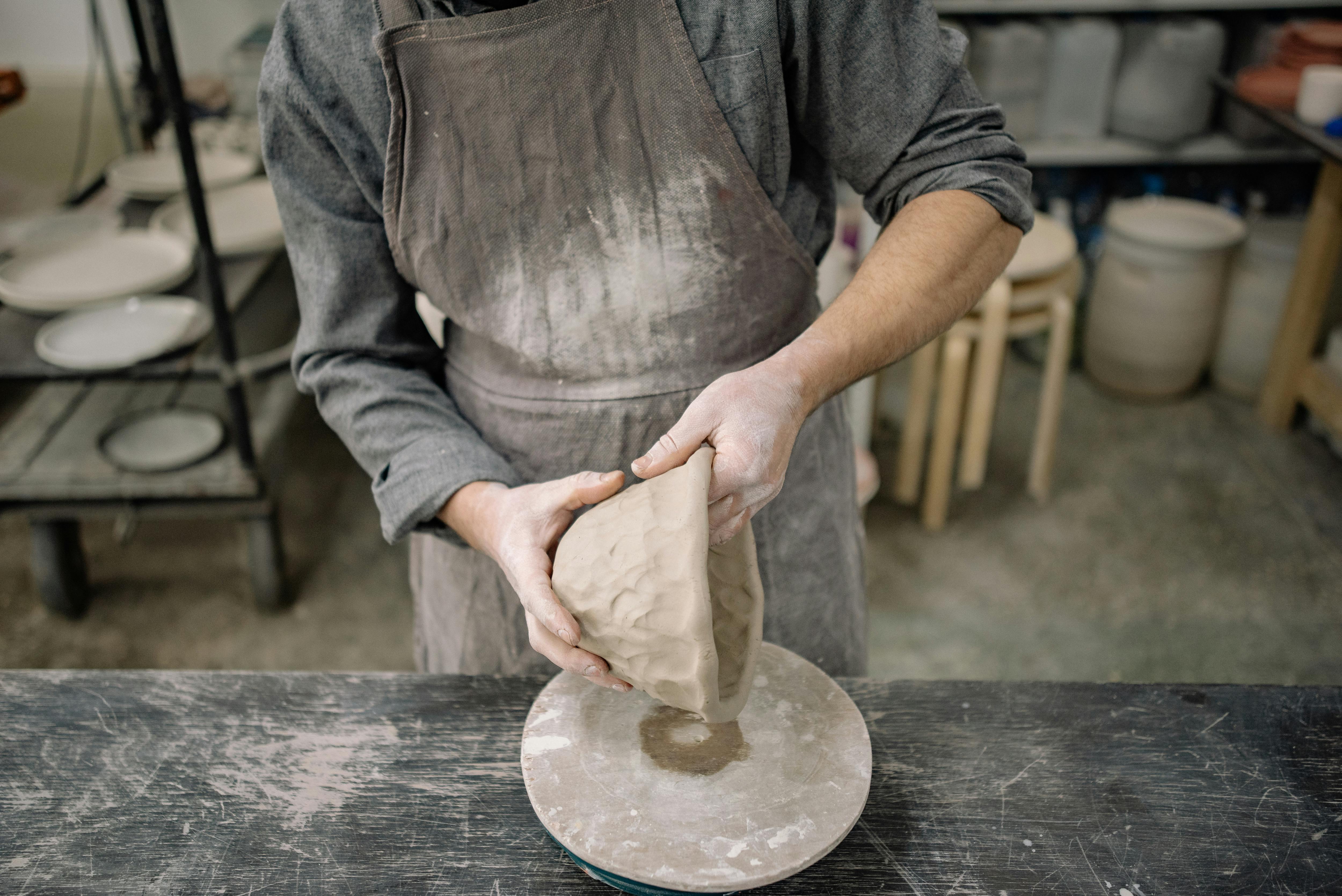 A potter attentively molds clay on a wheel in a traditional workshop environment.