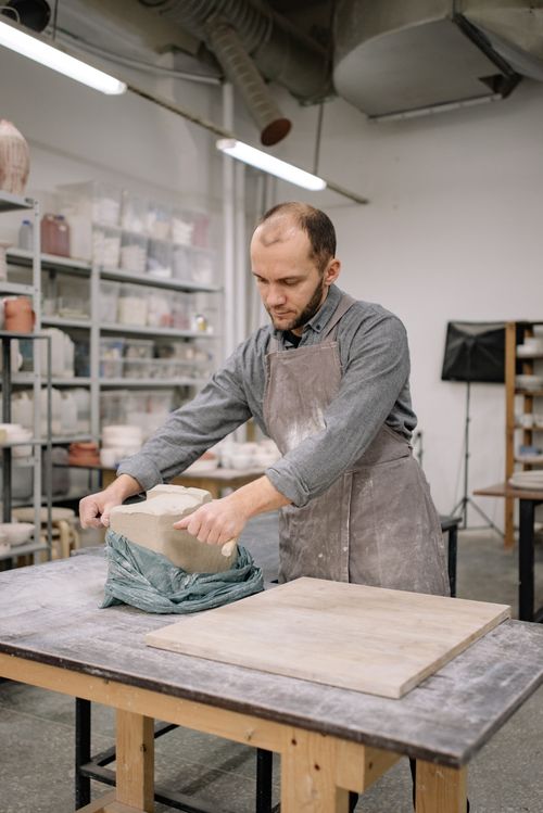Free A skilled artisan shaping clay in a workshop, creating from blocks at a workbench. Stock Photo