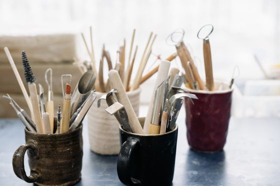 Pottery tools sorted in mugs on a workshop table, photo by Yan Krukau on Pexels