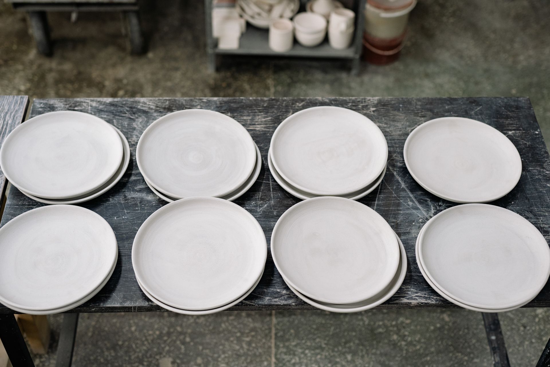 Collection of handcrafted earthenware plates on a pottery workshop table.