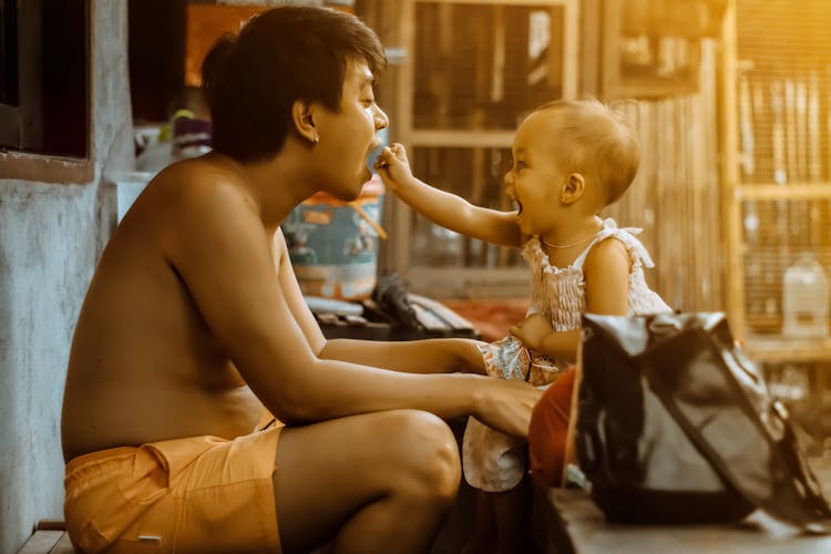 Toddler Feeding A Shirtless Man