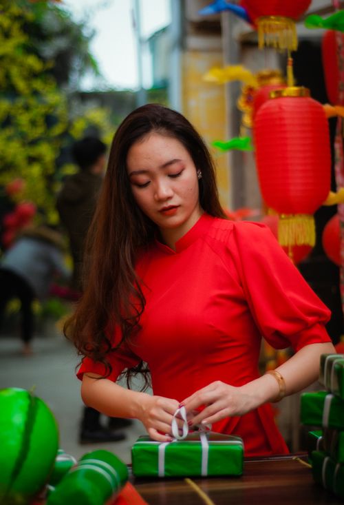 Free Woman in a traditional red dress preparing gifts during Chinese New Year celebration. Stock Photo