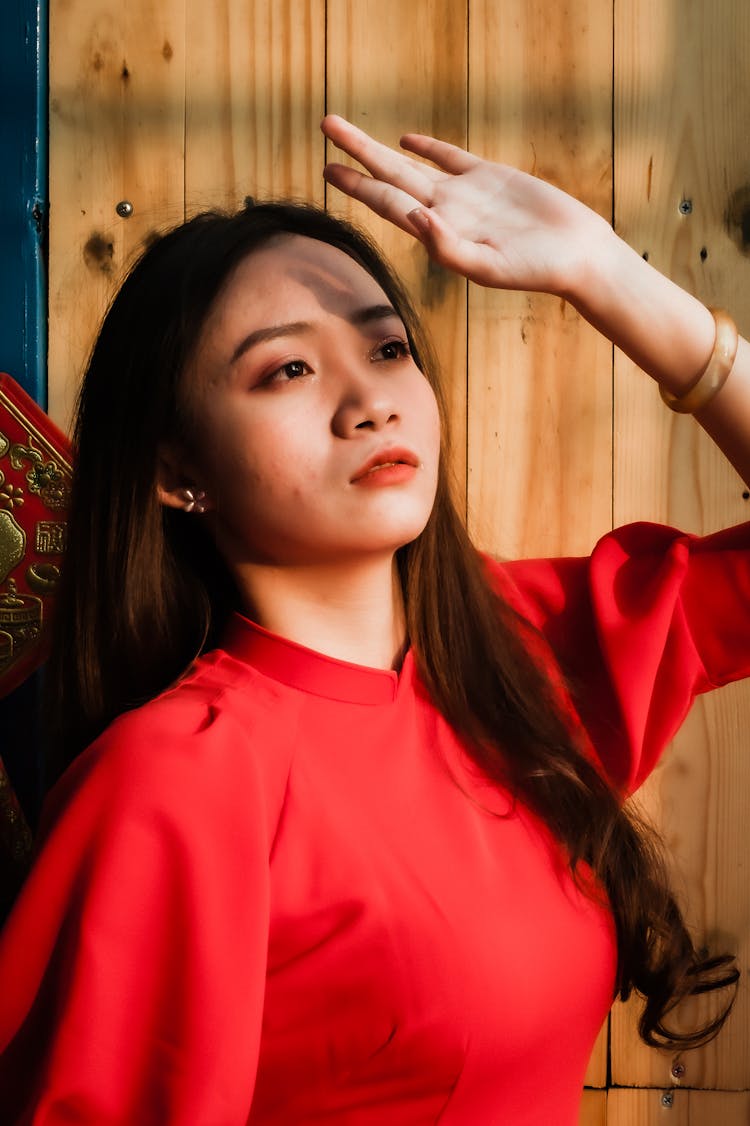 A Woman In Red Top Blocking The Light With Her Hand