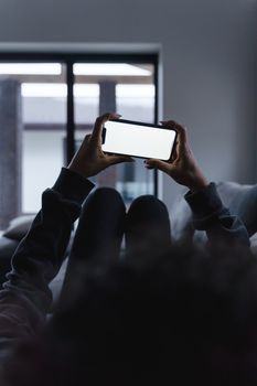 A cozy indoor scene of a person using a smartphone with a blank screen in low light.