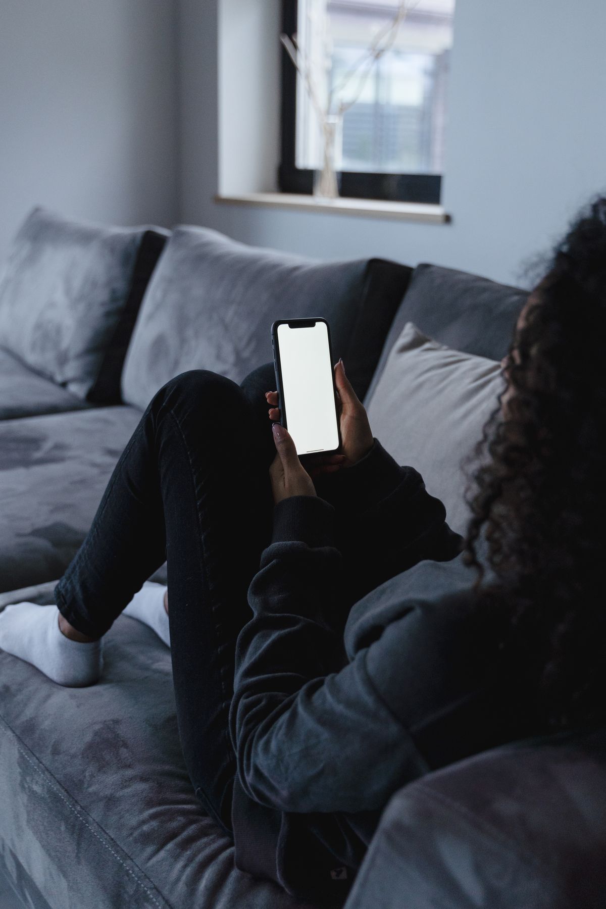 Person using a smartphone comfortably from a couch to complete an online application