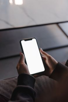 Close-up of hands holding a smartphone with a blank screen, perfect for mockup purposes.