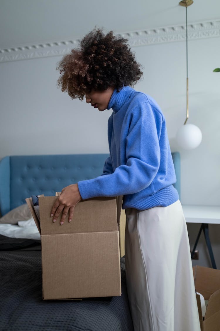 A Person Holding A Cardboard Box On The Bed