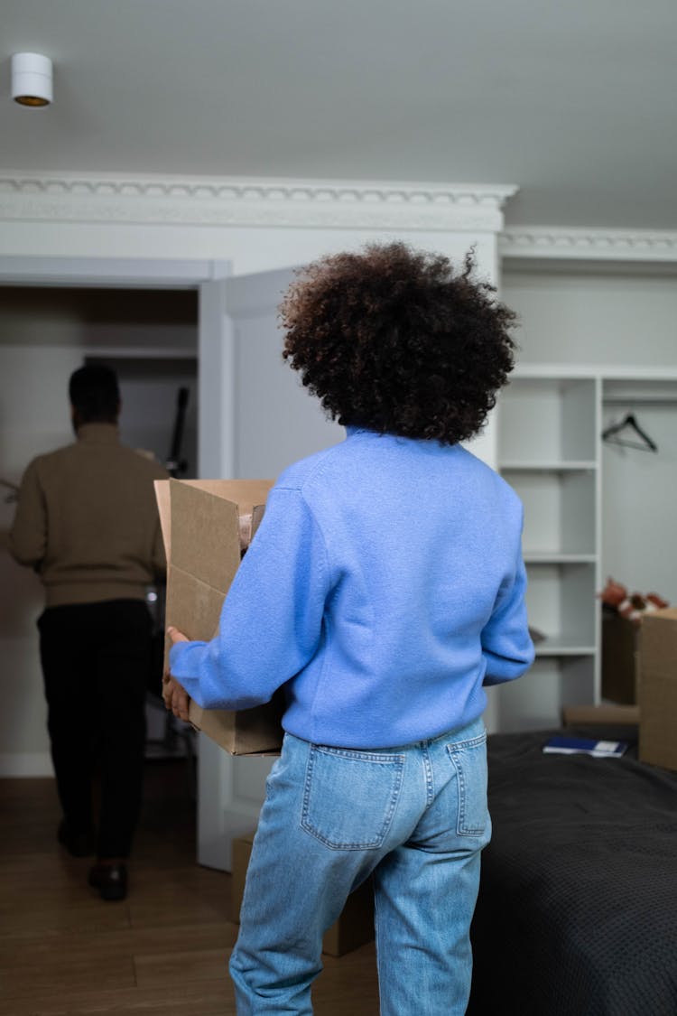 A Woman In Blue Sweater Carrying A Box