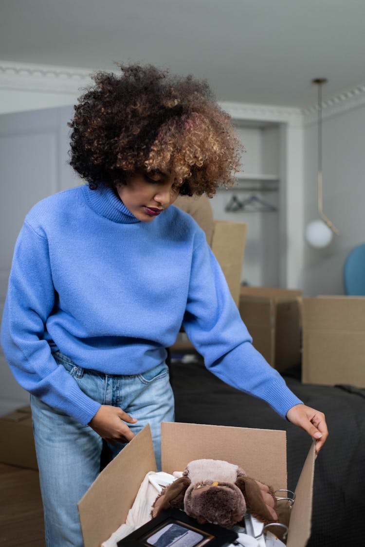 A Woman In Blue Sweater Carrying A Box