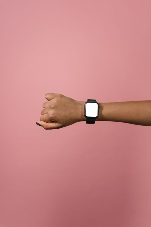 Free A smartwatch displayed on a person's wrist against a solid pink background. Stock Photo