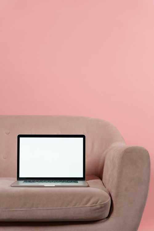 Free A minimalist setup featuring a modern laptop with a blank screen on a pink sofa in a studio setting. Stock Photo