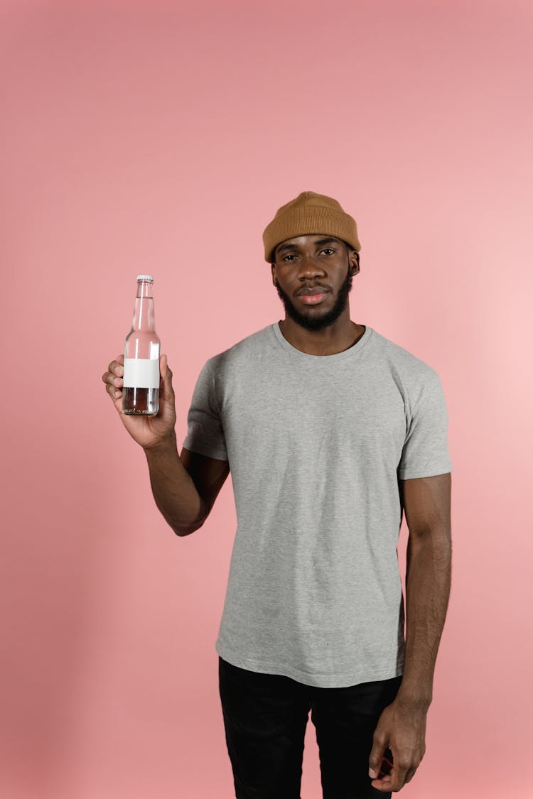 A Man In Gray Shirt Holding A Bottle