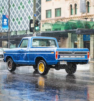 Blue pickup truck on a rainy street in Adelaide, showcasing classic automotive style.