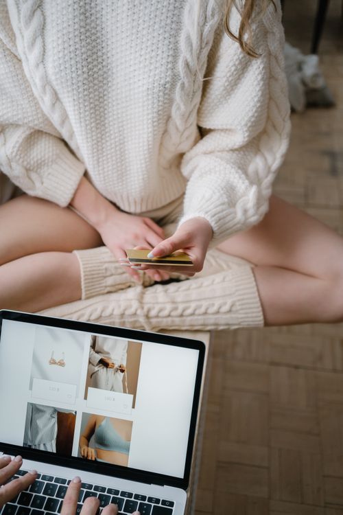 Free A woman in cozy attire shopping online using a laptop and credit card indoors. Stock Photo