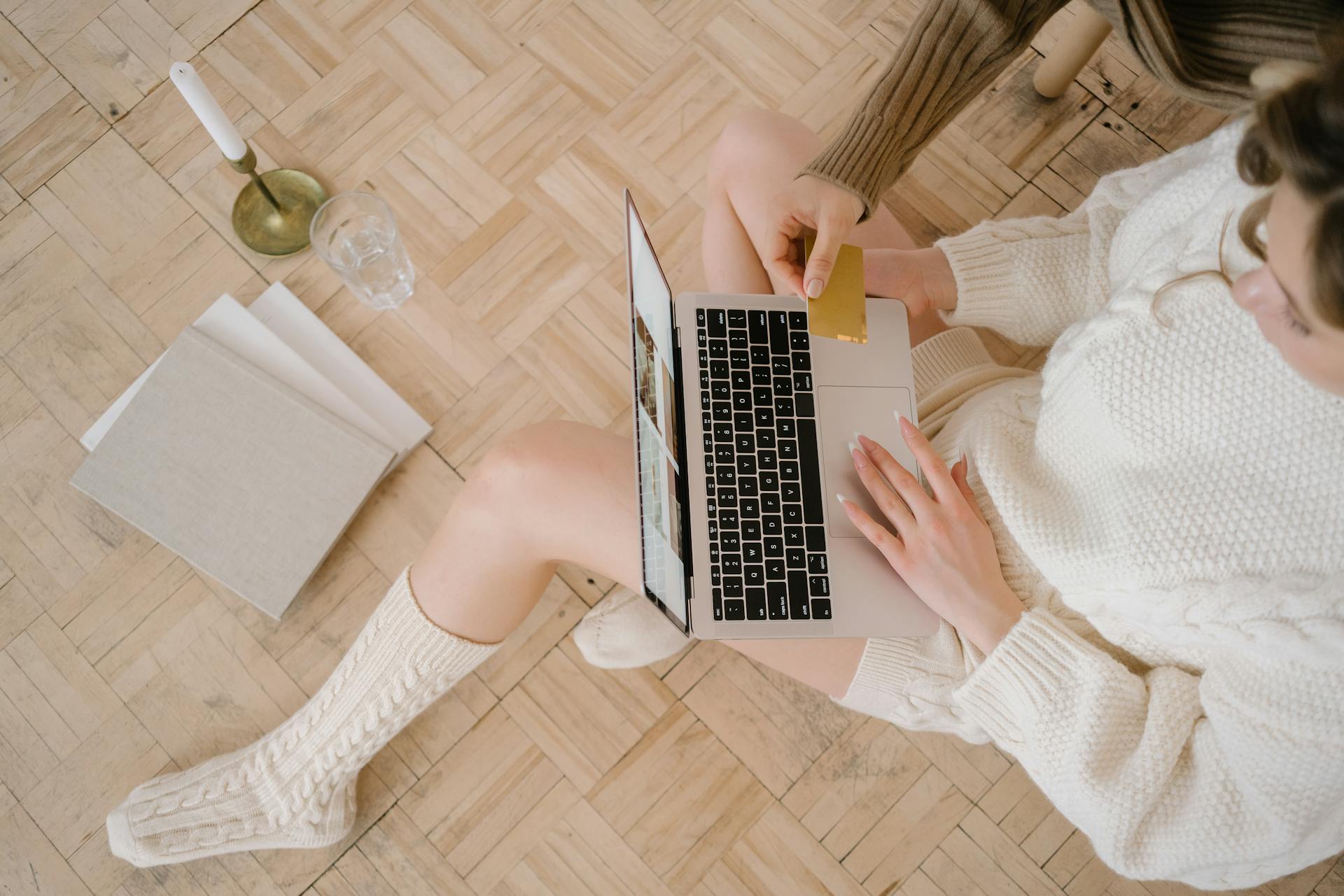 Overhead view of a woman using a laptop for online shopping at home.