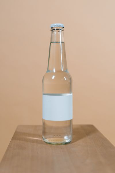 Blank-label glass bottle on a warm studio backdrop — photo by Tima Miroshnichenko on Pexels