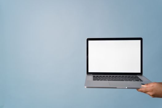 A person holding a laptop with a blank screen against a blue background, perfect for mockups.