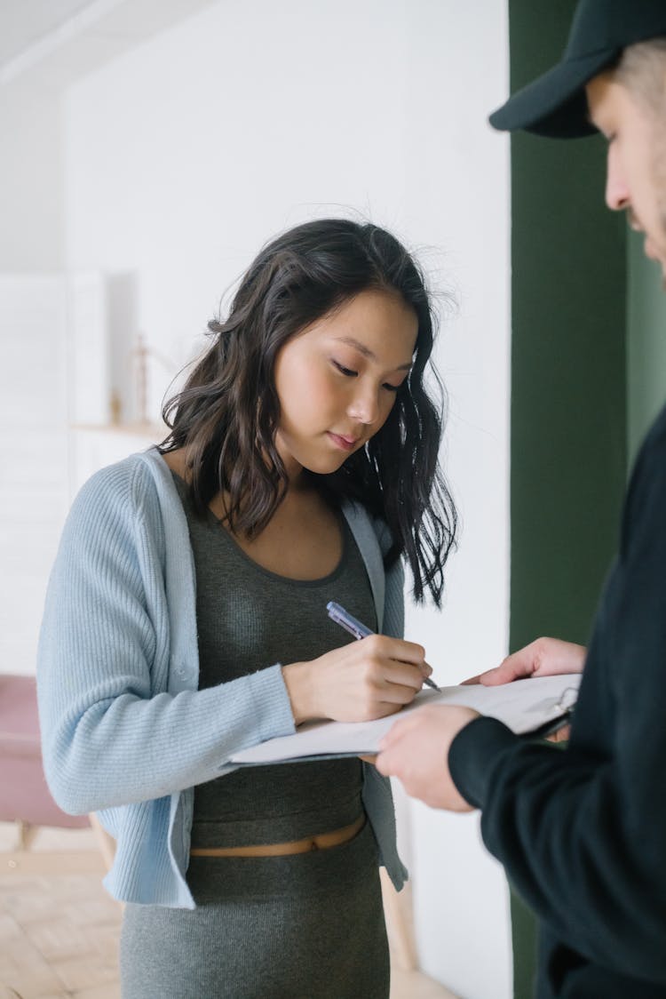 A Woman Signing A Document