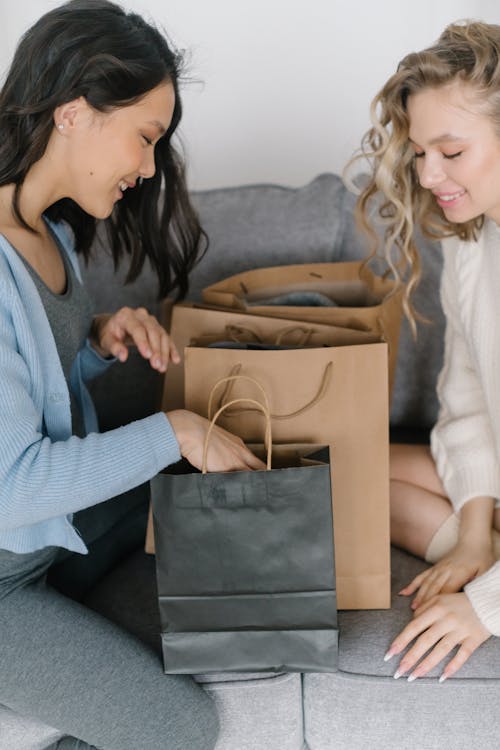 Women Looking at the Paper Bags while Sitting on the Couch