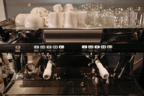 Free Close-up of a commercial espresso machine with cups and glasses stacked on top, ready for coffee brewing. Stock Photo