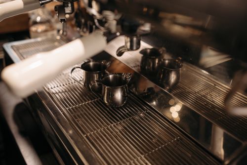 Free A detailed view of an espresso machine with metal frothing jugs ready for use in a coffee shop. Stock Photo
