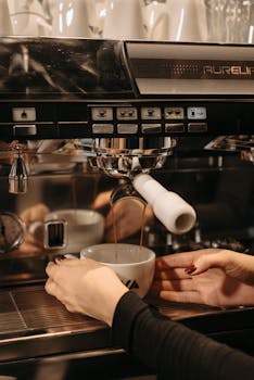 A detailed view of a barista's hands using an espresso machine to brew coffee.