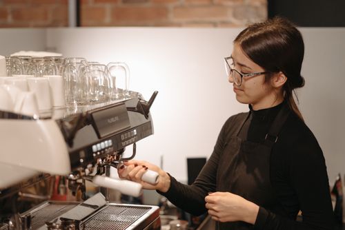 Free A barista skillfully preparing coffee using a professional espresso machine indoors. Stock Photo