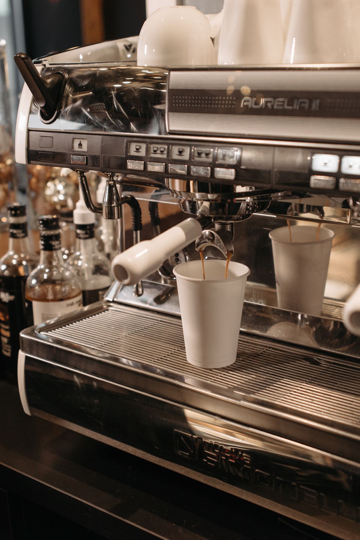Espresso pouring into cups from a commercial coffee machine