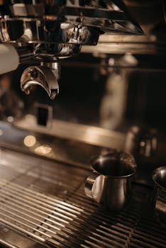 Close-up of a professional espresso machine brewing coffee into a metallic cup.