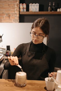 A dedicated barista adds the finishing touch to a cappuccino in a cozy cafe setting.
